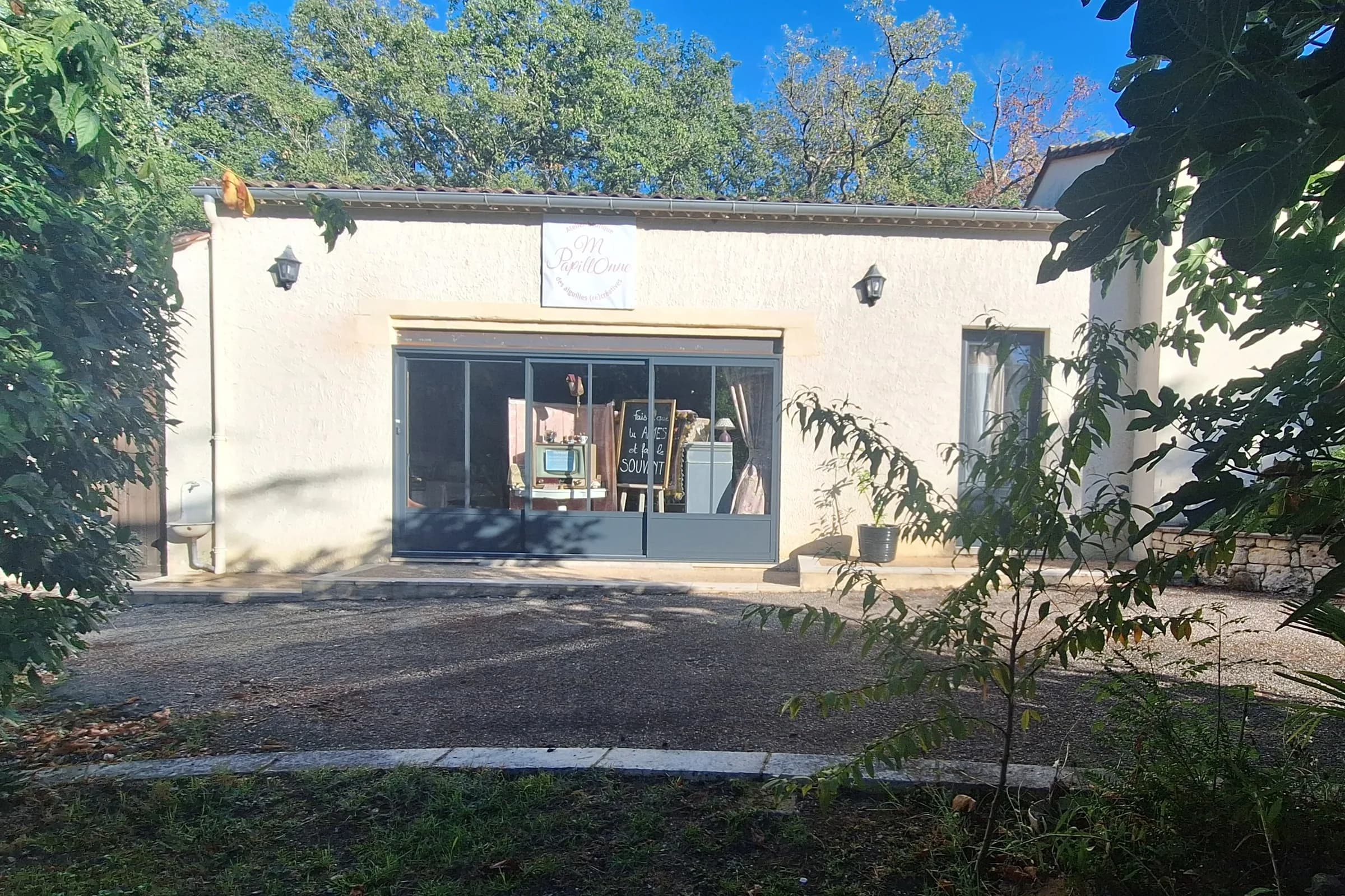 Même façade ouverte par une large baie vitrée à menuiseries grises, devenue vitrine d'un atelier boutique