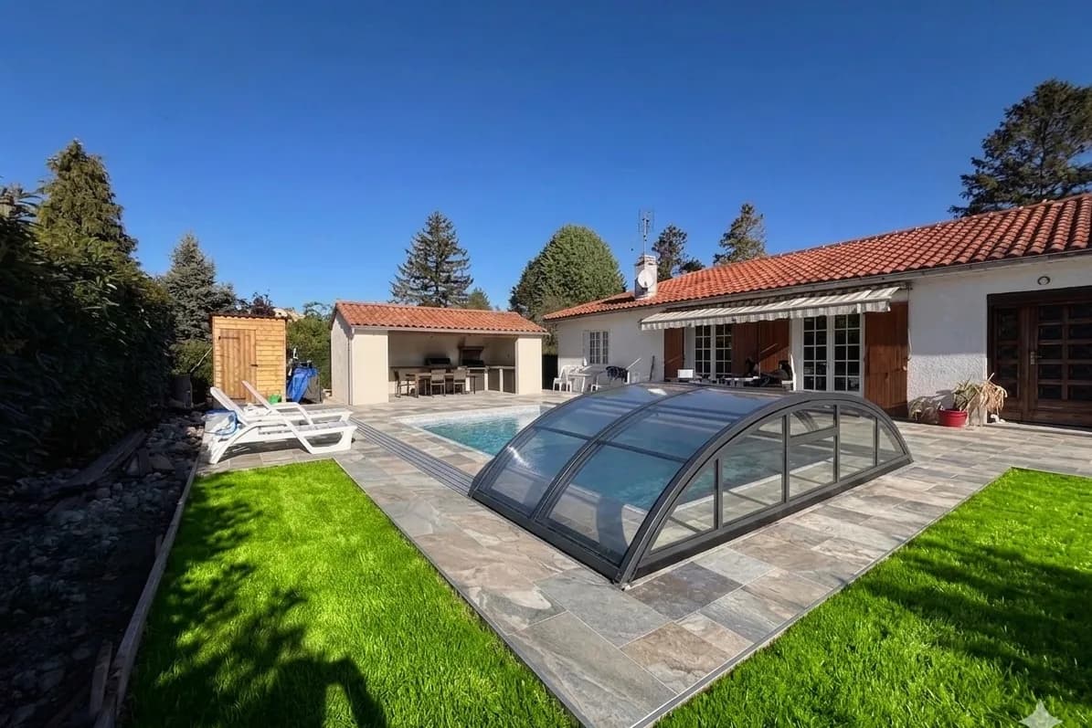 Piscine sous abri télescopique, terrasse en pierre et cuisine d'été couverte à l'arrière d'une maison